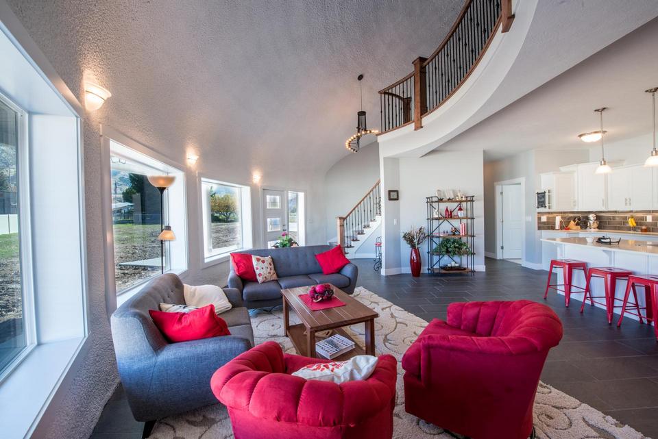 The great room in Arcadia Dome Home with the sweeping staircase and curved balcony.