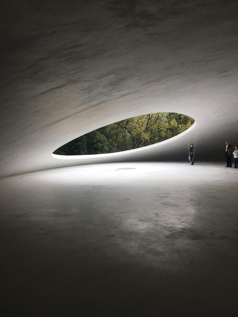 Beautiful light falls through round opening into the concrete shell of the Teshima Art Museum
